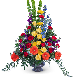 Tall mixed flower arrangement in a dark vase with orange gerberas and yellow roses