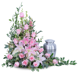 Pink roses and lilies arranged beside a silver urn