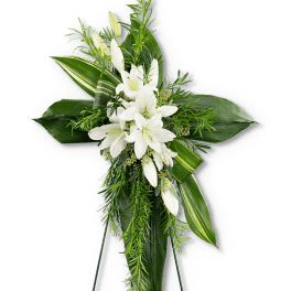 White lilies and greenery arranged in a cross-shaped spray