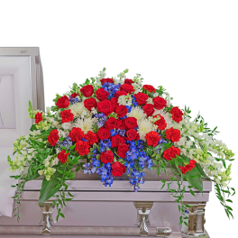 Casket spray with red roses, white flowers, and blue accents