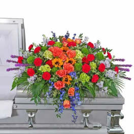 Colorful floral casket spray with roses, carnations, and purple spikes