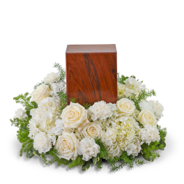 White roses and hydrangeas arranged around a wooden urn