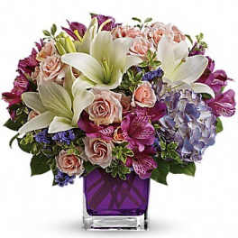 Bouquet of lilies, roses, hydrangea, and purple flowers in a square vase