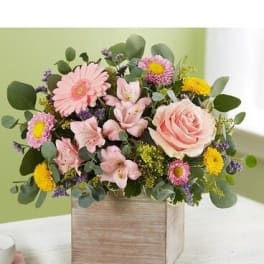 Pink and yellow mixed flower arrangement in a wooden box