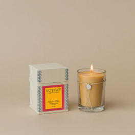 Lit candle in a glass tumbler beside its box