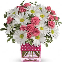Pink roses and white daisies arranged in a pink square vase
