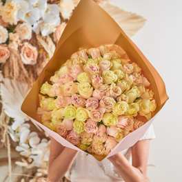 Large bouquet of pale pink and cream roses wrapped in tan paper