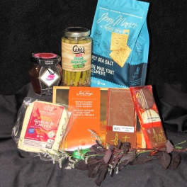 Gift basket with assorted packaged snacks and a jar of pickles