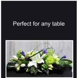 Low floral centerpiece with white lilies, tulips, and purple blooms