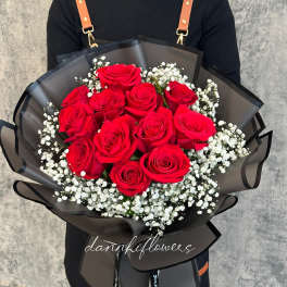 Bouquet of red roses with white baby's breath in black wrap
