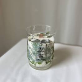 Glass candle jar with eucalyptus-themed label and white wax