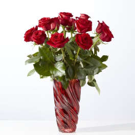 Red roses arranged in a tall red glass vase