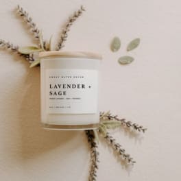 Lavender and sage scented candle in a glass jar with dried botanicals