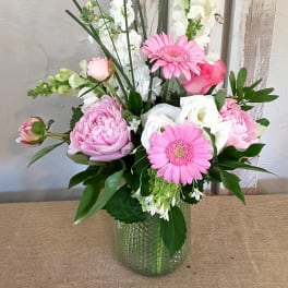 Pink and white flowers arranged in a glass vase