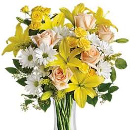 Bouquet of yellow lilies, peach roses, and white daisies in a clear glass vase