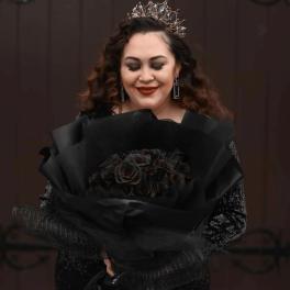 Woman holding a bouquet of dark roses wrapped in black paper