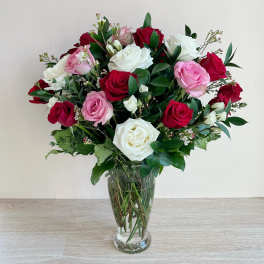 Bouquet of red, pink, and white roses in a clear glass vase