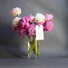 Pink and white bouquet in a clear glass vase with a hanging tag