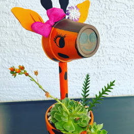 Decorative orange painted planter with a succulent and flower accents