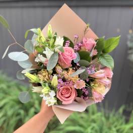 Handheld bouquet of pink roses, white blooms, and eucalyptus in blush wrap
