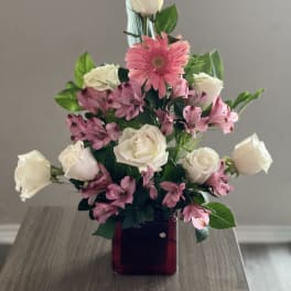 Pink and white roses with pink alstroemeria in a red glass vase