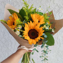 Handheld bouquet of sunflowers with small white daisies and brown paper wrap