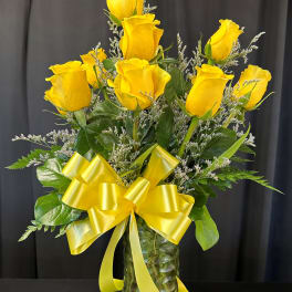 Yellow roses in a glass vase with a yellow ribbon bow