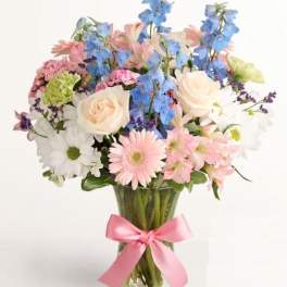 Mixed pastel bouquet in a clear glass vase with a pink ribbon