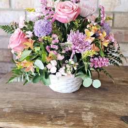 Pink and purple mixed flower arrangement in a white basket