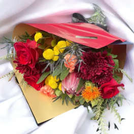 Bouquet of red roses and mixed blooms wrapped in red paper