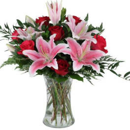 Bouquet of pink lilies and red roses in a clear glass vase