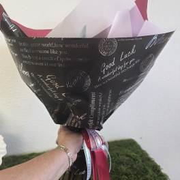 Wrapped bouquet with pink and white paper and ribbon