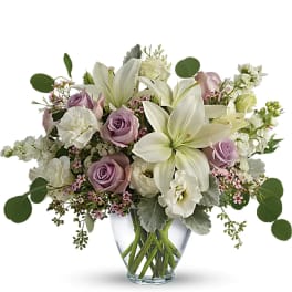 Lavender roses and white lilies in a clear glass vase