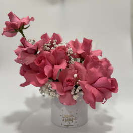 Pink roses arranged in a white cylindrical box with baby's breath
