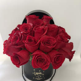 Red roses arranged in a black hatbox with a rope handle