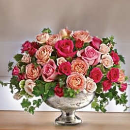 Pink and peach roses arranged in a silver pedestal vase