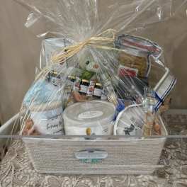 Gift basket with candles, snacks, and a teddy bear wrapped in clear cellophane