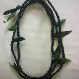 Braided dark green floral lei with scattered leaves