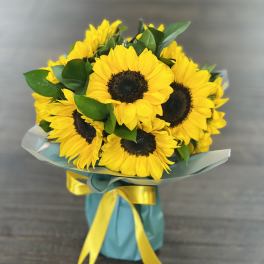 Bouquet of yellow sunflowers wrapped with blue paper and ribbon