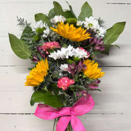 Bouquet of yellow, white, pink, and purple flowers tied with a pink ribbon