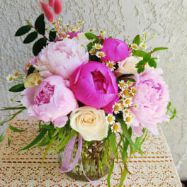 Pink and cream bouquet in a glass vase with small white daisies