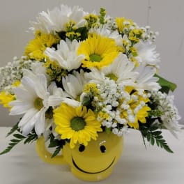 Yellow and white daisy bouquet in a smiley-face mug