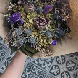 Dried bouquet with purple blooms and thistle in brown paper