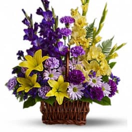 Purple and yellow mixed flower arrangement in a wicker basket