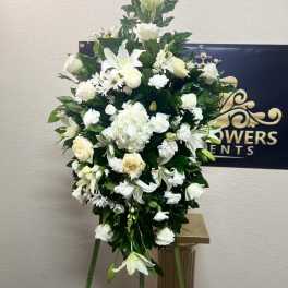 White floral standing spray with lilies and roses on an easel