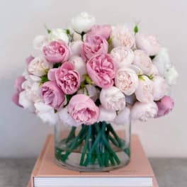 Pink and white roses arranged in a clear glass vase