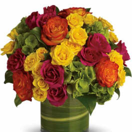 Mixed roses in yellow, orange, and magenta arranged in a glass vase