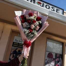 Handheld bouquet of red and pink roses wrapped in pink paper