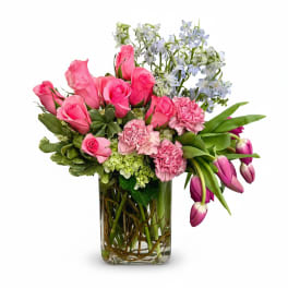 Pink roses and tulips in a glass vase with blue flowers