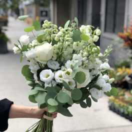 White bouquet with roses and small white blooms, wrapped in eucalyptus
